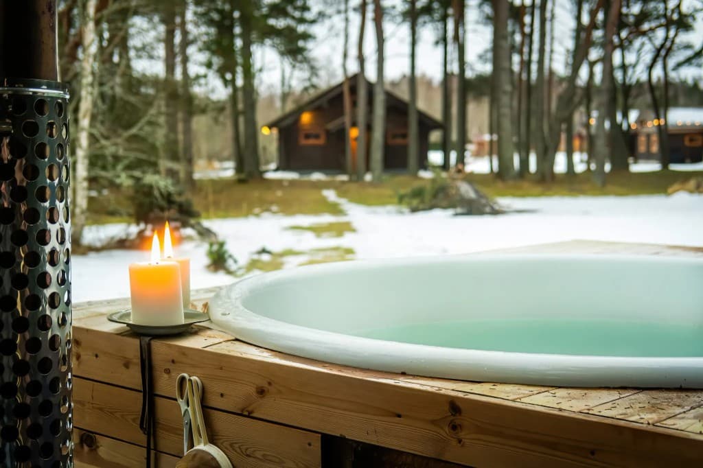 Kümblustünn talvisel õhtul metsa ja puhkemajade taustal